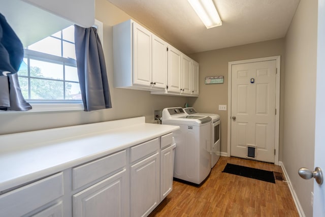 laundry room featuring cabinets, independent washer and dryer, and light wood-type flooring