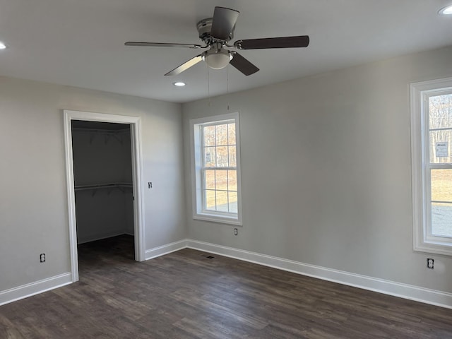 unfurnished bedroom featuring multiple windows, a walk in closet, ceiling fan, and a closet