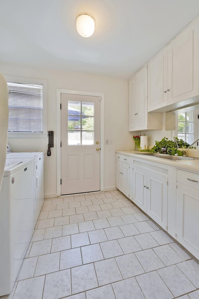 clothes washing area featuring washer and clothes dryer, sink, light tile patterned floors, and cabinets