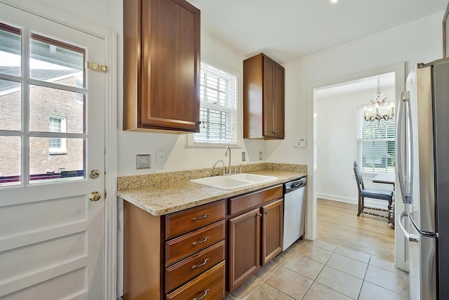 kitchen featuring sink, stainless steel appliances, a wealth of natural light, and an inviting chandelier