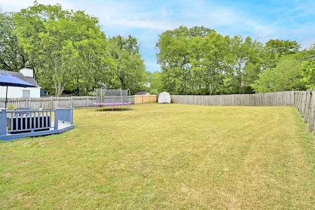 view of yard with a trampoline, a shed, and a wooden deck