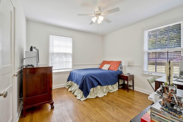 bedroom with hardwood / wood-style floors, multiple windows, and ceiling fan