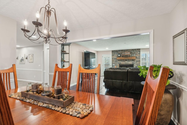 dining area with hardwood / wood-style flooring, a fireplace, a textured ceiling, and a notable chandelier