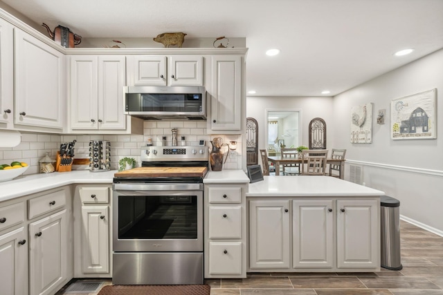 kitchen featuring tasteful backsplash, white cabinets, stainless steel appliances, and wood-type flooring