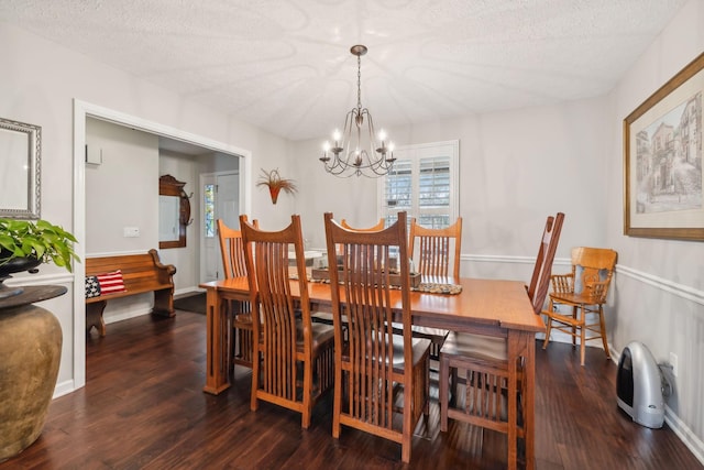 dining area with a textured ceiling, dark wood-type flooring, and a notable chandelier