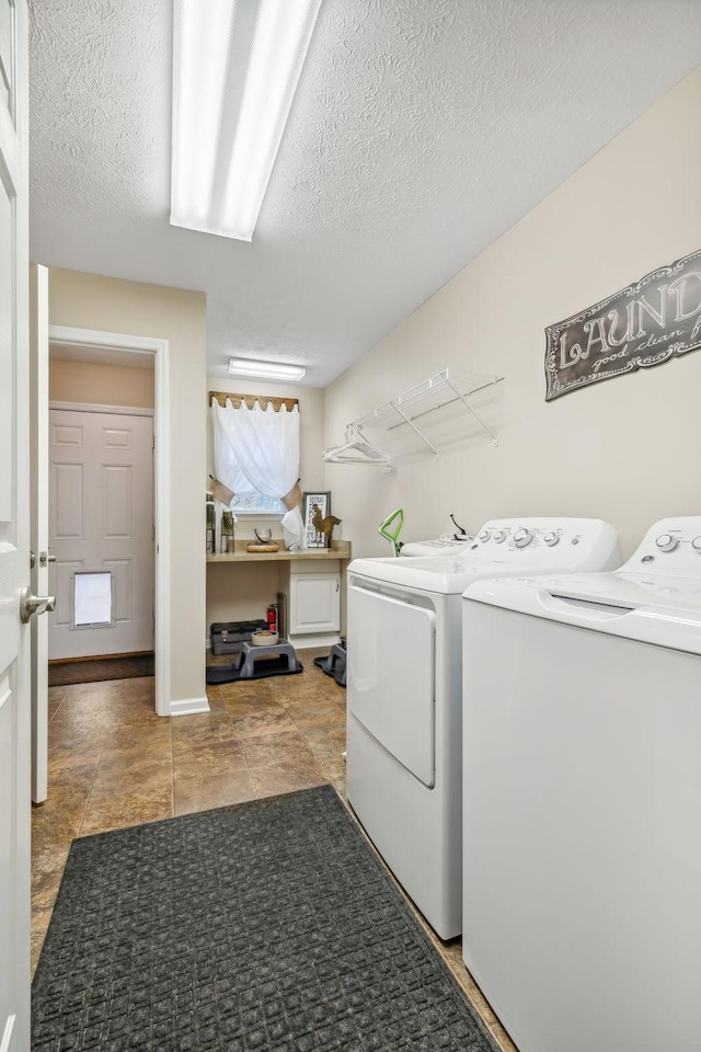 laundry area with washing machine and dryer, light tile patterned floors, and a textured ceiling