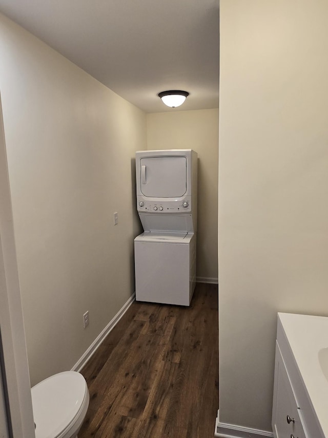 bathroom with toilet, vanity, stacked washer / drying machine, and hardwood / wood-style flooring