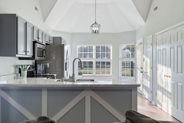 kitchen featuring kitchen peninsula, gray cabinetry, sink, decorative light fixtures, and light hardwood / wood-style floors