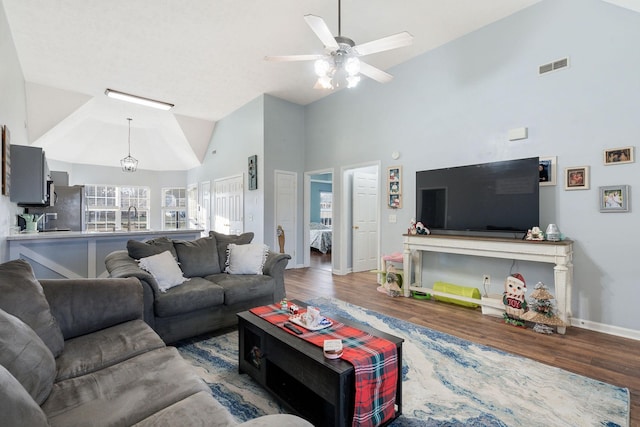 living room with ceiling fan, wood-type flooring, sink, and high vaulted ceiling