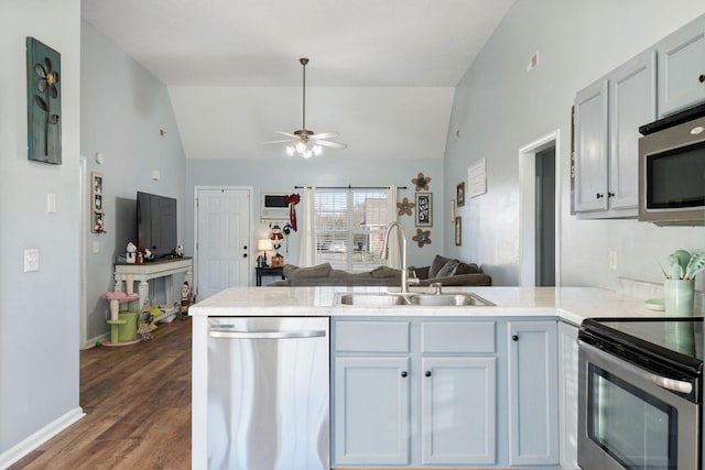 kitchen featuring sink, vaulted ceiling, dark hardwood / wood-style floors, appliances with stainless steel finishes, and kitchen peninsula