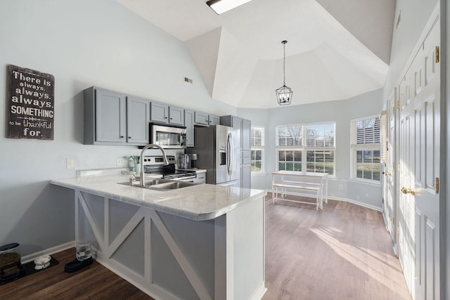 kitchen with hardwood / wood-style floors, kitchen peninsula, stainless steel appliances, and hanging light fixtures