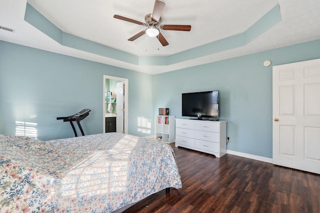 bedroom featuring connected bathroom, dark hardwood / wood-style floors, a raised ceiling, and ceiling fan