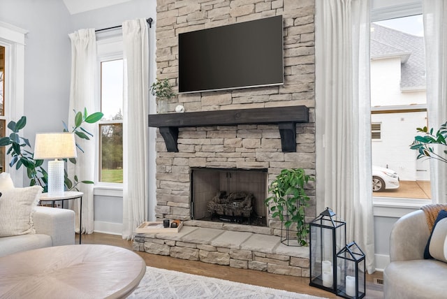 living room with a fireplace, light hardwood / wood-style flooring, and a wealth of natural light