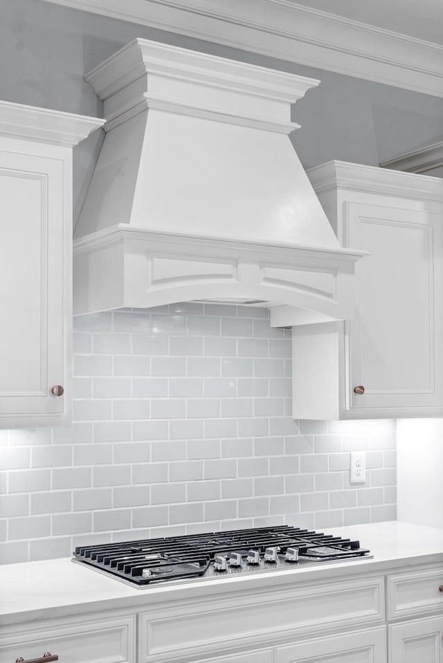 kitchen with white cabinets, backsplash, stainless steel gas cooktop, and crown molding