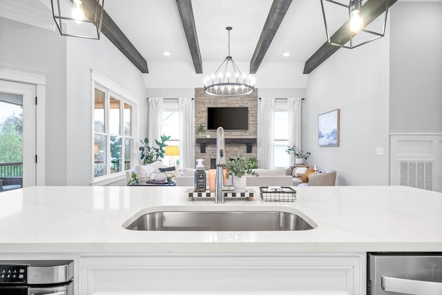 kitchen with light stone countertops, beam ceiling, pendant lighting, and sink