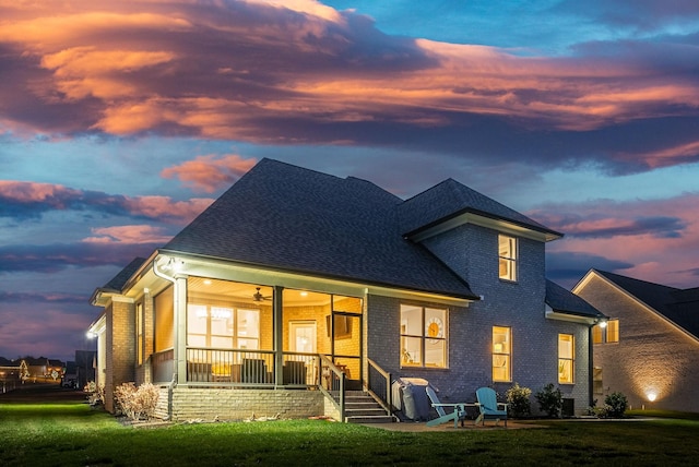 back house at dusk with a yard and ceiling fan