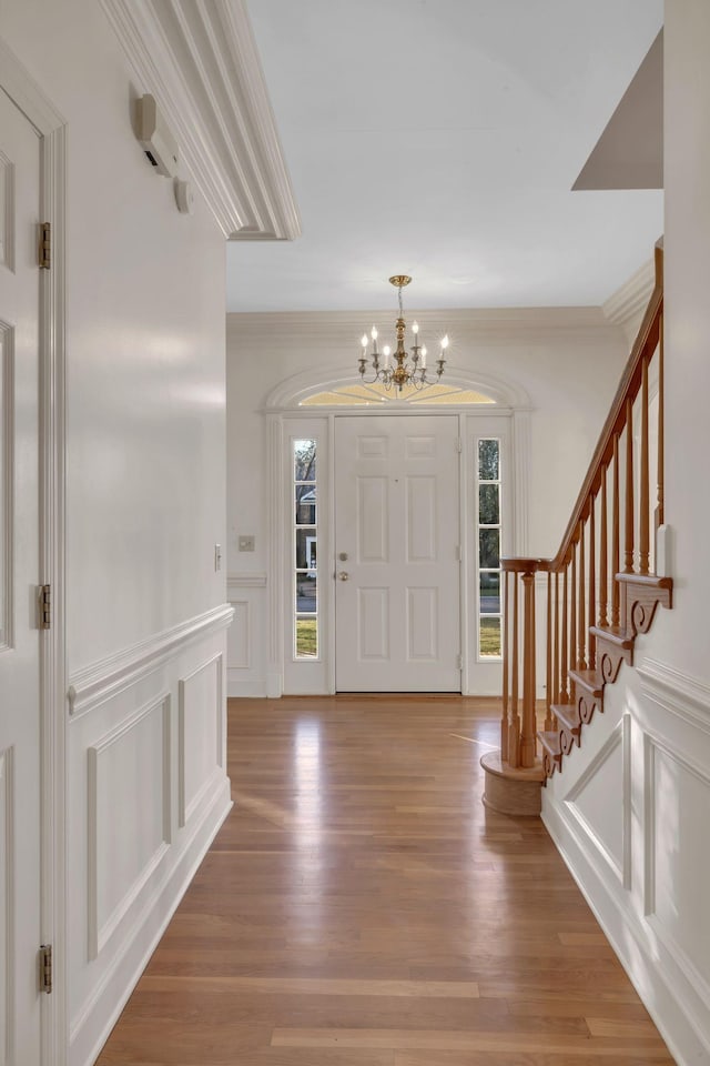 entrance foyer featuring crown molding, wood-type flooring, and a notable chandelier