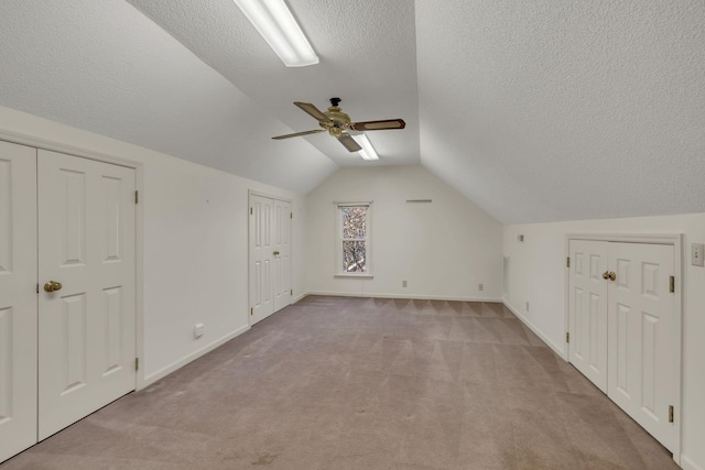 additional living space featuring ceiling fan, light colored carpet, lofted ceiling, and a textured ceiling