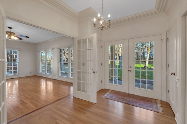 doorway featuring crown molding, french doors, ceiling fan with notable chandelier, and light wood-type flooring