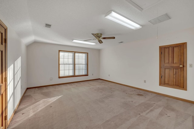 carpeted spare room with a textured ceiling, vaulted ceiling, and ceiling fan