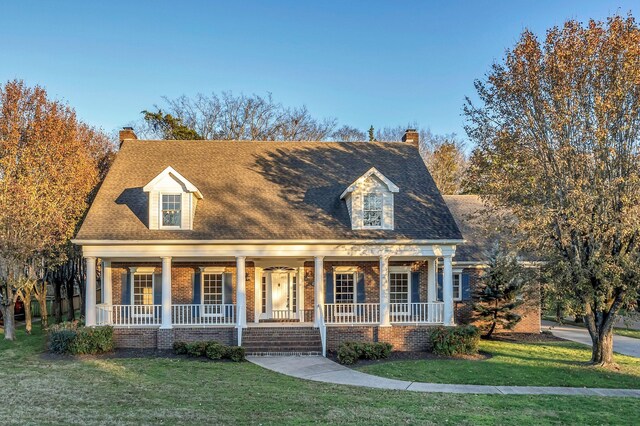 new england style home with a porch and a front lawn