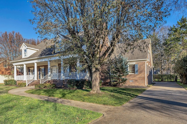 cape cod home with a front yard and a porch