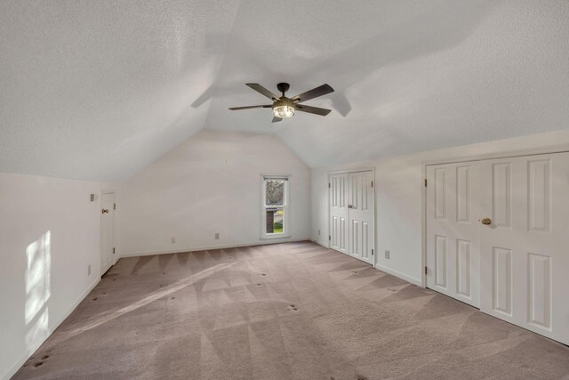 bonus room with a textured ceiling, ceiling fan, light colored carpet, and vaulted ceiling