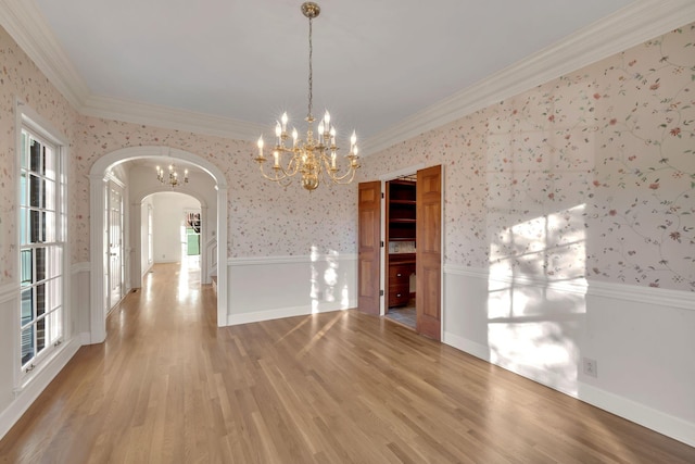 unfurnished dining area with wood-type flooring, ornamental molding, and a chandelier