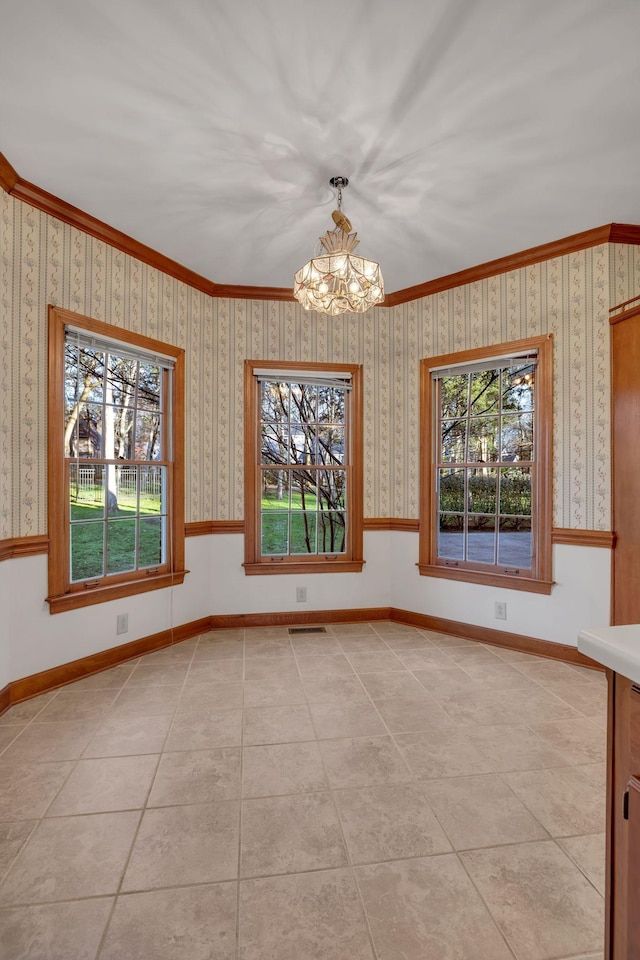 unfurnished dining area with an inviting chandelier, a wealth of natural light, ornamental molding, and light tile patterned flooring