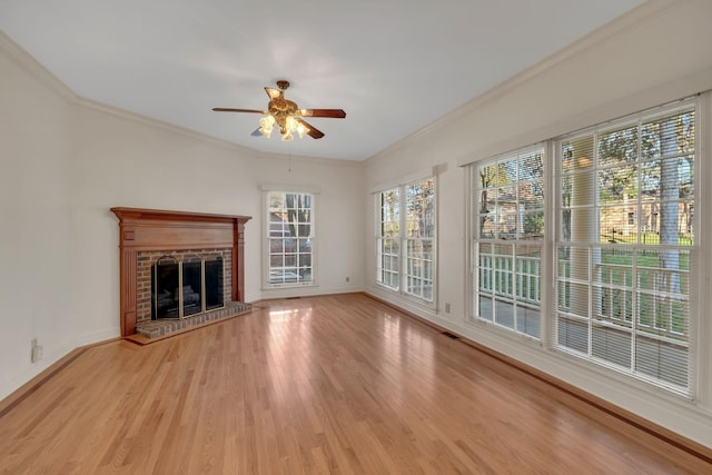 unfurnished living room with ceiling fan, light wood-type flooring, crown molding, and a brick fireplace