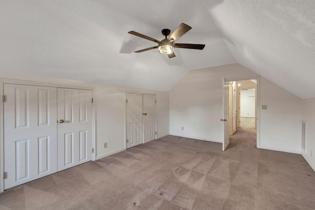 additional living space with a textured ceiling, ceiling fan, light colored carpet, and lofted ceiling