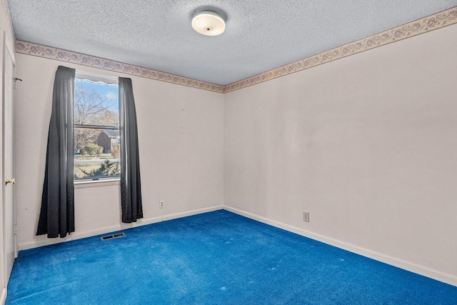 carpeted empty room featuring a textured ceiling