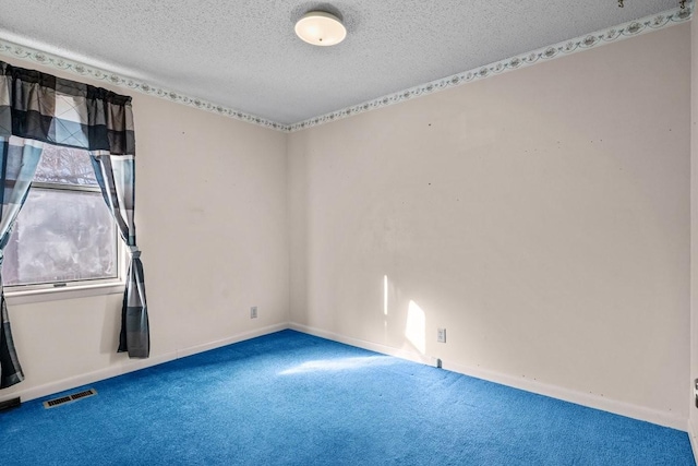 carpeted empty room featuring a textured ceiling