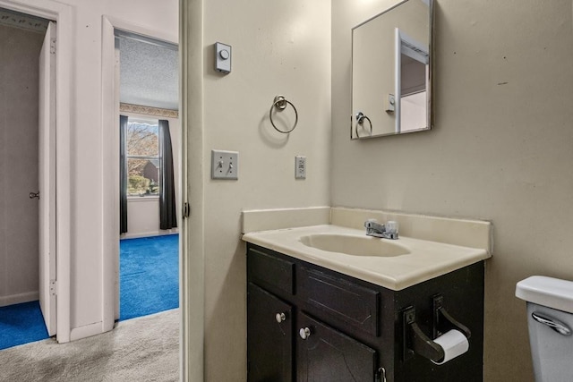 bathroom featuring vanity, a textured ceiling, and toilet