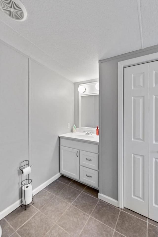 bathroom with tile patterned flooring, a textured ceiling, and vanity