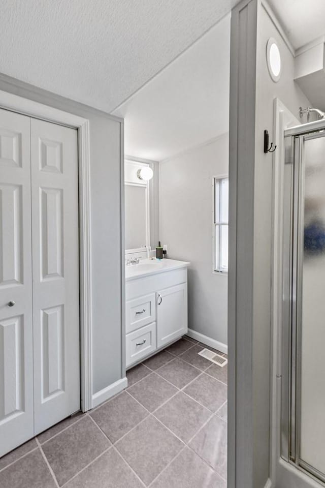 bathroom with vanity, tile patterned floors, and a shower with door