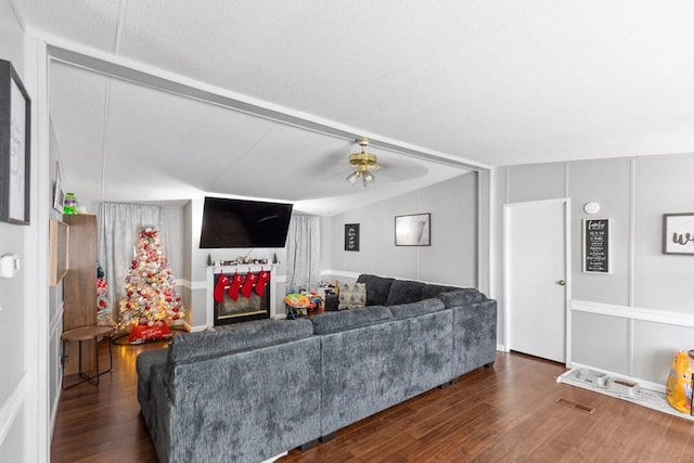 living room with lofted ceiling, ceiling fan, and dark wood-type flooring