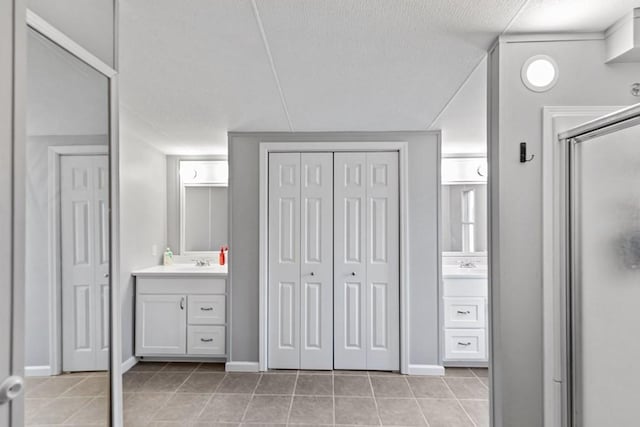 bathroom featuring tile patterned flooring, a textured ceiling, vanity, and a shower with door