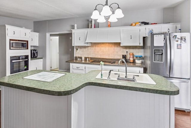 kitchen with pendant lighting, black appliances, a center island with sink, sink, and white cabinetry