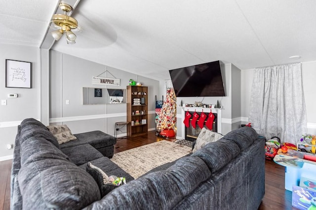 living room featuring dark wood-type flooring, ceiling fan, and lofted ceiling