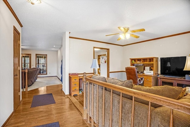 living room with a textured ceiling, light hardwood / wood-style flooring, ceiling fan, and ornamental molding