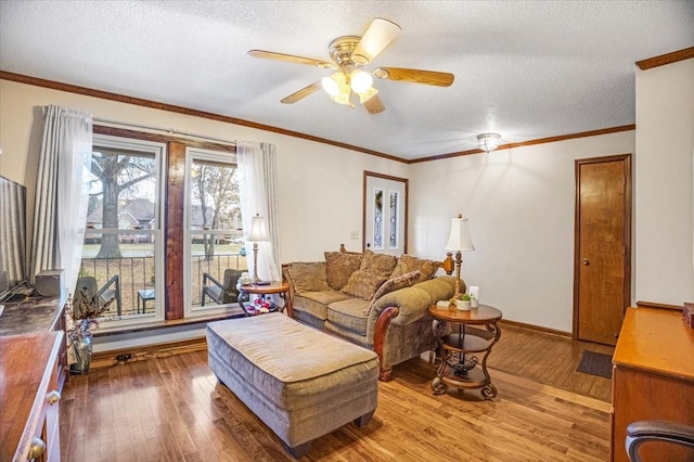 living room featuring ceiling fan, wood-type flooring, a textured ceiling, and ornamental molding