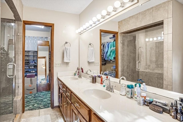 bathroom featuring tile patterned flooring, vanity, a textured ceiling, and walk in shower