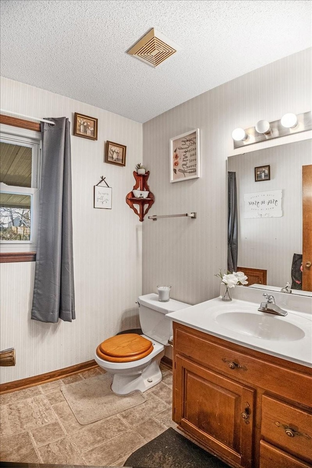 bathroom with vanity, toilet, and a textured ceiling