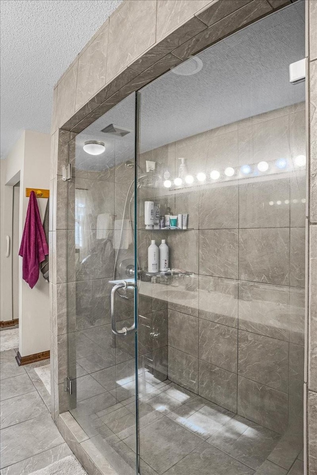 bathroom with a shower with shower door and a textured ceiling