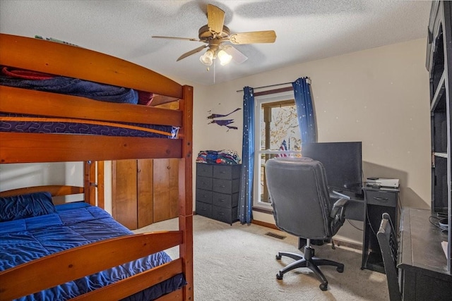 carpeted bedroom with ceiling fan and a textured ceiling