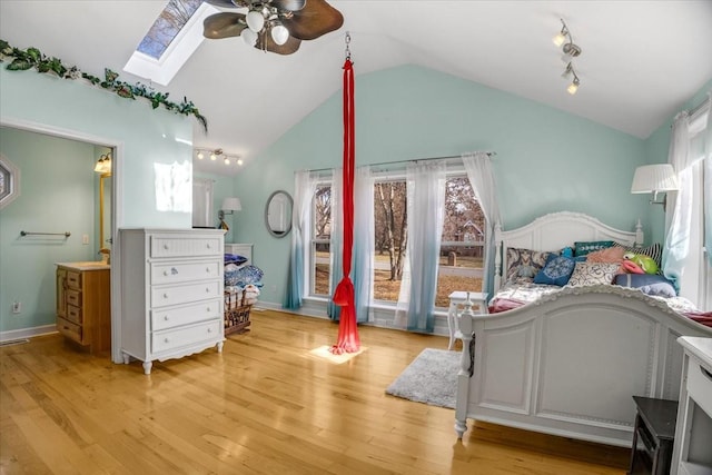 bedroom with ceiling fan, light hardwood / wood-style floors, lofted ceiling with skylight, and track lighting