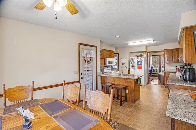 dining area with a textured ceiling, ceiling fan, and sink