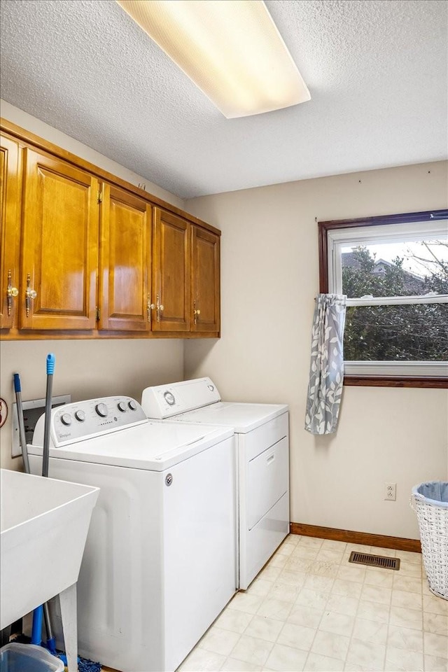 laundry area featuring sink, cabinets, a textured ceiling, and washing machine and clothes dryer