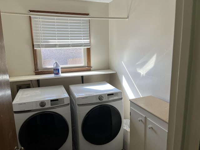 clothes washing area featuring washer and dryer and cabinets